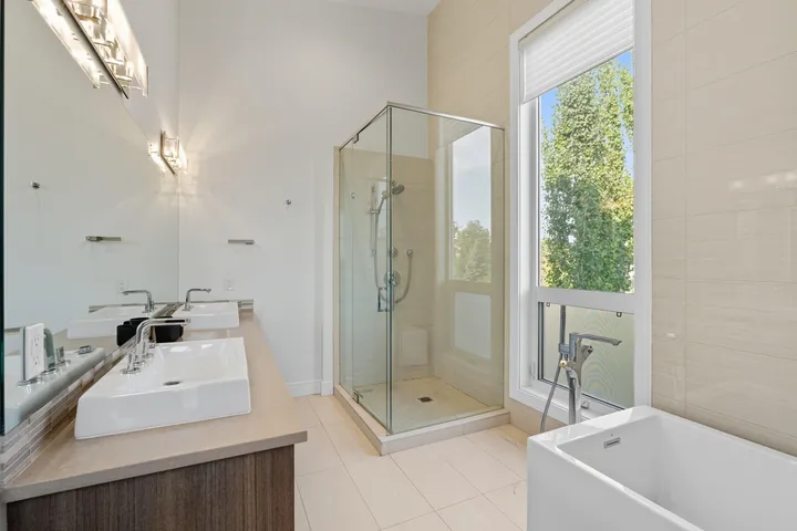 Spa-style ensuite bathroom with a glass shower, soaker tub, and large window