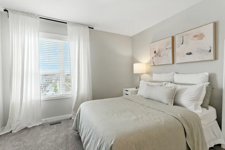 Bedroom with sheer curtains and a large window overlooking the downtown skyline