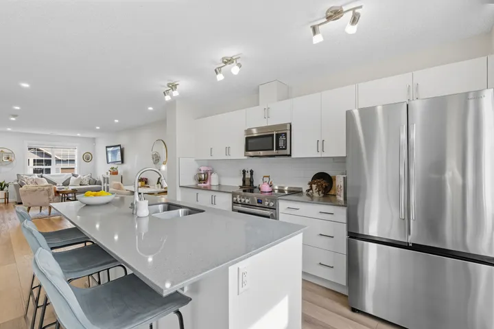 Open-concept white kitchen with island seating opening onto the living room