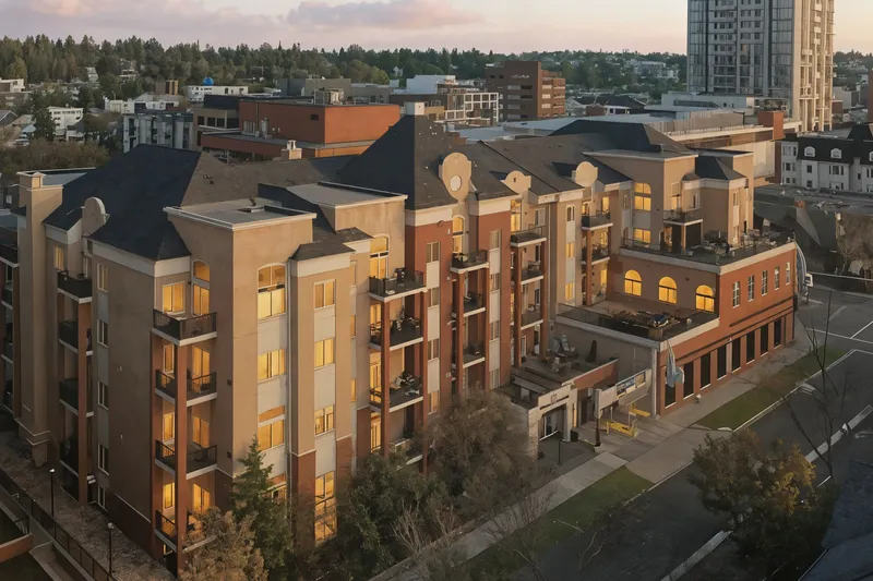 Twilight aerial drone photo of a Calgary condo building with the downtown skyline behind it